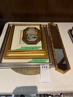 Framed artworks with size labels and bamboo-style mirror all displayed on a table