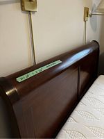 Photo showing headboard of dark wood sleigh bed frame with measurement tape indicating dimensions.