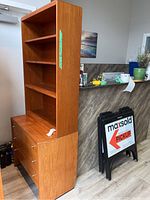 Front and side view of assembled two-piece bookcase cabinet with three drawers base and four open shelves in teak veneer