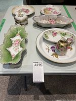 Photo of all ceramic china pieces grouped on a table showing various shapes and floral designs.