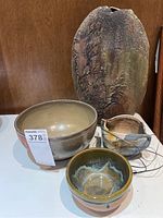 Front view showing all four ceramic items: large beige bowl, small glazed bowl, tall textured vase, and hanging plant pot.