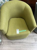 Front view of green bucket chair showing curved back and arm design with seat cushion, including measurement label.