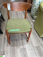 Front view of chair showing curved wood backrest and green upholstered seat