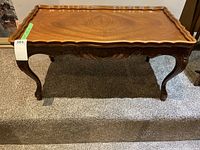 Front view of wood coffee table showing scalloped edge and carved apron.