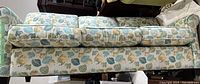 Full side view of couch showing leaf patterned upholstery and three cushions.