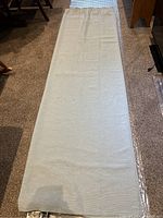 Photo showing one light blue curtain panel fully spread on floor, displaying fabric texture and size