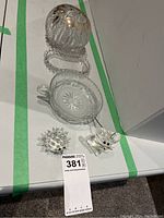 Photo showing all five items: two Swarovski crystal animal figurines and three glass serving pieces including a bowl with handle, a ridged plate, and a spherical bowl.