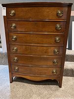 Front view of the wood dresser showing five drawers with brass handles and overall condition.