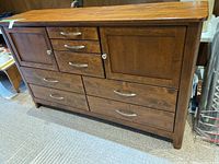 Front view of wooden dresser with cabinet doors, drawers, and metal handles.