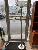 Full view of the floor lamp showing metal stand, base, and both lamp shades near a window.