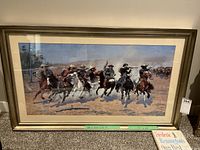 Framed old west picture showing cowboys on horseback in a dynamic scene.