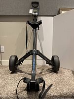 Full view of the black Bag Boy golf cart showing three wheels and handle, with footrest and straps.