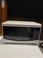 White RCA microwave oven with black window and keypad control panel.