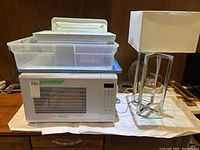 Panasonic microwave, lamp, plastic trays and storage bins arranged together on a surface.