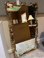 Front view of mirror leaning against wall showing full frame and reflective surface.