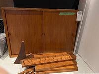 Disassembled teak cabinet components including shell, shelves, sliding doors, rails, brackets and hardware