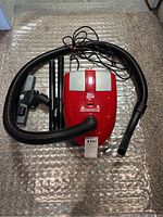 Overview of the entire vacuum with hose and attachments laid out on the floor.