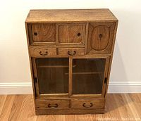 Full frontal view of tea chest showing upper sliding doors, small drawers, lower glass sliding doors and bottom drawers