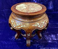 Front and side view of antique Chinese rosewood jardiniere stand with carved mother-of-pearl bird and cherry branch inlays, mother-of-pearl dots, cabriole legs and ring stretcher on dark blue fabric background.