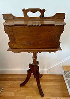 Front view of the standing wooden sewing or magazine stand showing the closed hinged compartments and carved base