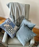 Cashmere throw draped over a chair with three blue and patterned cushions
