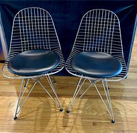 Front view of both chairs showing chrome wire shell and black leather pads