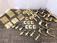 Full set of Lawrence Hardware brass door fittings arranged to show variety and quantity including hinges, strike plates, lever handles, cylinders.