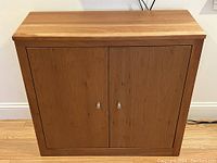 Front view of solid cherry wood cabinet with two doors and brushed steel knobs.