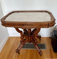 Full view of rectangular marble topped table and carved wooden base
