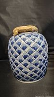 Front view of blue and white porcelain ginger jar with geometric pattern and paper-wrapped lid.