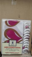 Packaged fabric shower curtain showing design and included rings