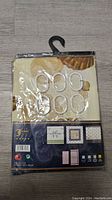 Photo of packaged fabric shower curtain showing front design with seashell and starfish motif and included white rings.