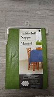 Front view of the green tablecloth packaged with label showing the product type and image of a blue tablecloth on a table.