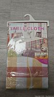 Front package view of brand new table cloth with colorful checked pattern and packaging showing the table and chairs.