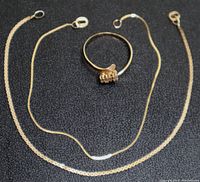 Two 14K gold bracelets and one 14K gold ring displayed on black background, showing full length of bracelets and stone setting on ring.