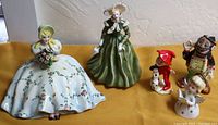 Five ceramic figurines including lady in white dress, lady in green dress, little devil, angel, and Kreiss rhinestone hobo