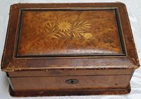 Photo of closed vintage wooden jewelry box showing inlaid floral design on lid and woodgrain paper edges with wear