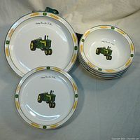 Two large and stack of four smaller John Deere tractor china plates.