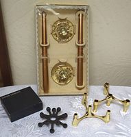 Three different styles of mid-century candleholders: Dansk black metal multi-candleholder, lucite gold flake candleholders in box, and gold-colored metal candleholders.