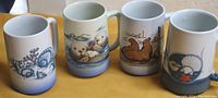 Four ceramic mugs, 5 inches high, showing front sea life designs.