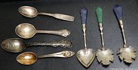 Top view showing all seven souvenir spoons with varying handle designs, including stone handles and engraved bowls