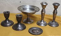 Wide view photo showing the full lot including the footed candy dish in the center, two pairs of candleholders on each side, and small round dish in front.