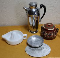Photo shows the chrome coffee pot, white glass juicer, Mexican pottery lidded pot, aluminum bowl, and aluminum trivet.