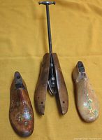 Overview of all three wooden shoe forms arranged side by side, one large adjustable tool in the center and two smaller decorative pieces flanking it