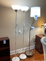 Full view of three floor lamps showing design and sizes with white background wall.