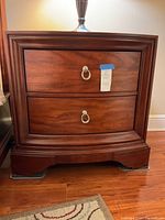 Front view of nightstand showing curved front and two drawers with metal ring pulls