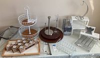 Wide view of assorted kitchen organization items on table including wire baskets, jars, trays, lazy susans, and more.