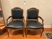 Front view of two wooden leather captain chairs with decorative rivets, placed side by side.