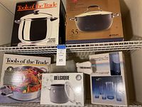 Full view of top shelf items including Tools of the Trade 12-quart stockpot and Anolon 5.5-quart stockpot boxes, along with acrylic glassware set and soup pot box.