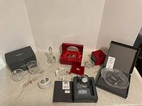 Overview photo showing multiple Waterford Crystal deco pieces including clock, bowls, perfume bottle, and train figurine, some in original boxes.